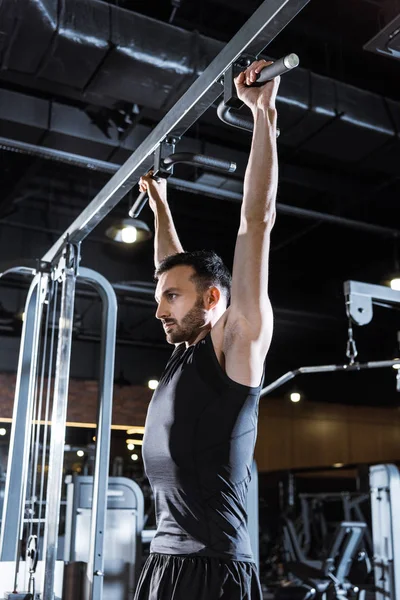 Low angle view of handsome athletic man doing pull up in sports center — Stock Photo