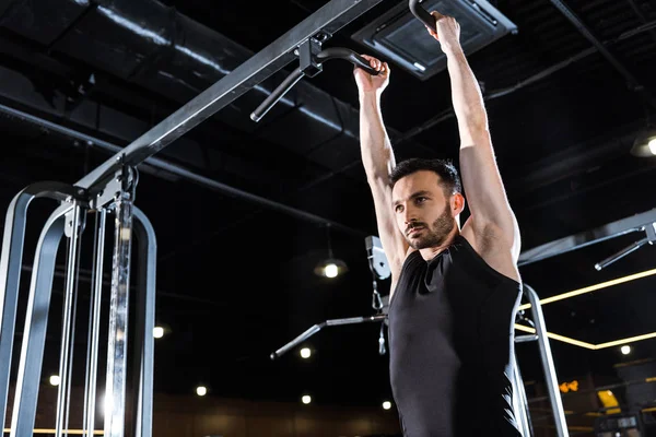 Low angle view of strong athletic man doing pull up in sports center — Stock Photo