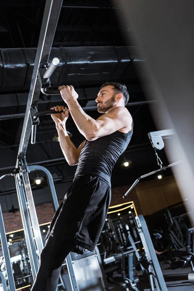 Low angle view of athletic man doing pull up in sports center — Stock Photo