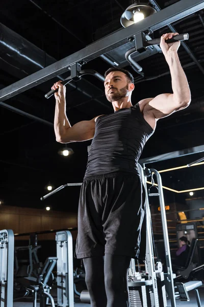 Low angle view of athletic sportsman doing pull up in sports center — Stock Photo