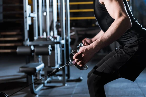 Ausgeschnittene Ansicht eines athletischen Mannes, der an Trainingsgeräten im Fitnessstudio trainiert — Stockfoto