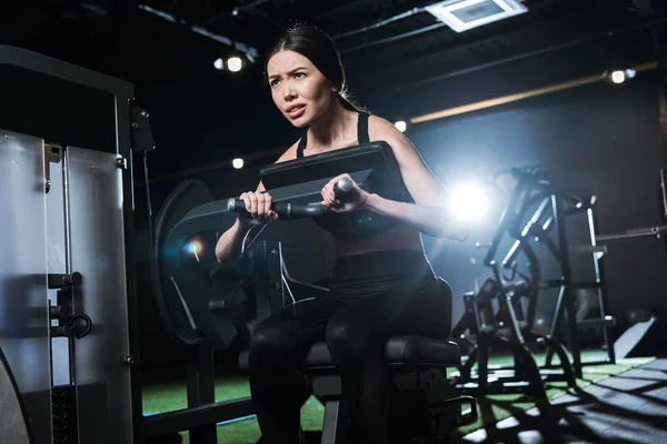 Low angle view of strong athletic woman exercising on training apparatus in gym — Stock Photo