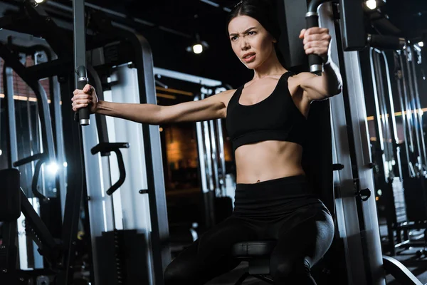 Athletic sportswoman exercising on training apparatus in gym — Stock Photo