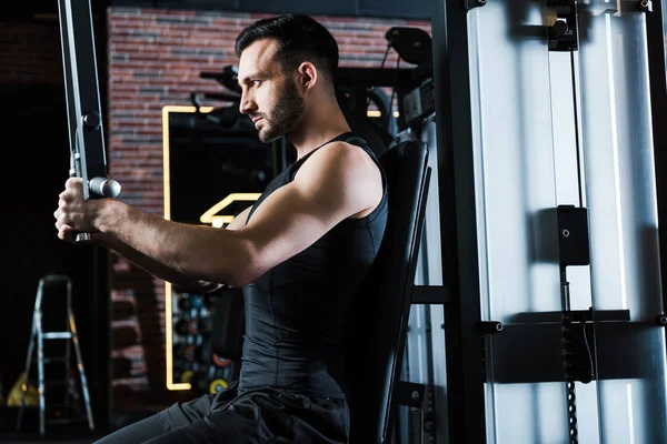 Schöner bärtiger Sportler, der an Trainingsgeräten im Fitnessstudio trainiert — Stockfoto