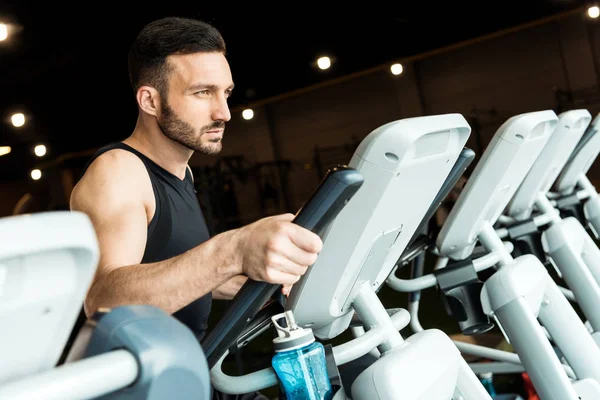 Selective focus of handsome bearded man working out on exercise bike — Stock Photo