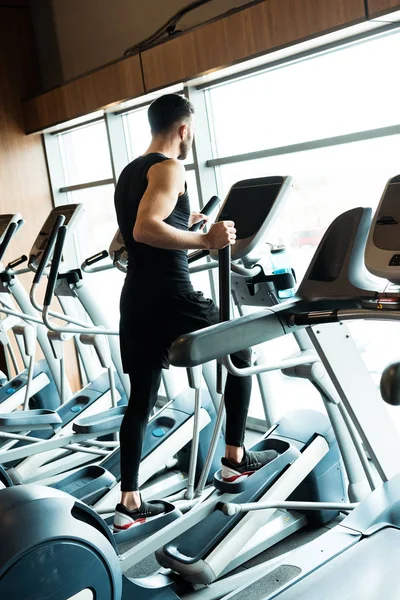 Low angle view of athletic and strong man working on out on exercise bike in gym — Stock Photo