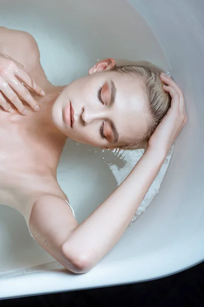 Top view of sexy nude woman with closed eyes in clear water in bathtub — стоковое фото