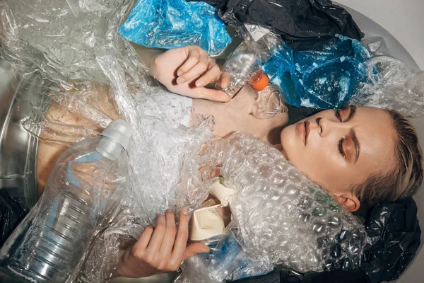 Top view of woman among plastic waste in bathtub, eco concept — стоковое фото