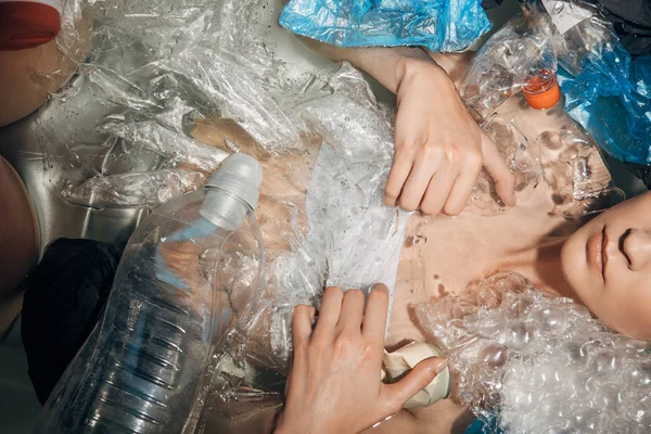 Visión parcial de la mujer entre los residuos de plástico en la bañera, concepto ecológico - foto de stock