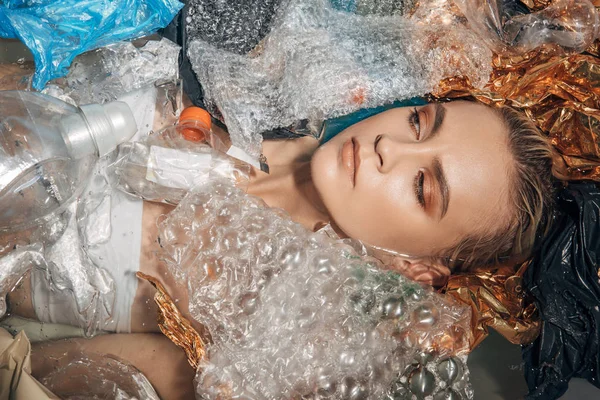 Vista superior de la mujer joven posando en bañera con basura de plástico, concepto ecológico - foto de stock