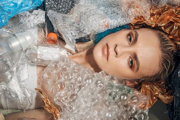Vista superior da mulher jovem na banheira com resíduos de plástico, conceito de poluição ambiental — Fotografia de Stock