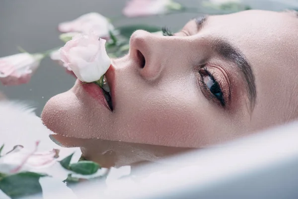 Bella donna sdraiata in acqua limpida con fiore in bocca — Foto stock