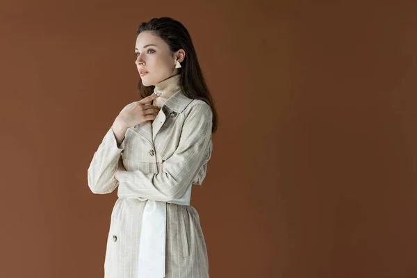 Модна жінка в траншеї пальто ізольована на коричневому з копіювальним простором — стокове фото
