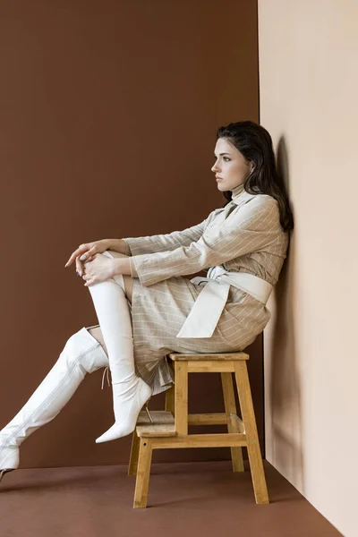 Vista lateral da mulher bonita e na moda sentada nas escadas, olhando para longe — Stock Photo