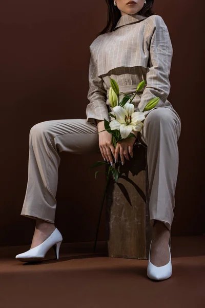 Vue à angle bas de la femme à la mode avec fleur dans les mains assis sur la boîte — Photo de stock