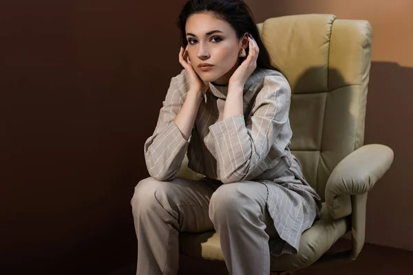 Side view of beautiful woman sitting on armchair, looking at camera — Stock Photo