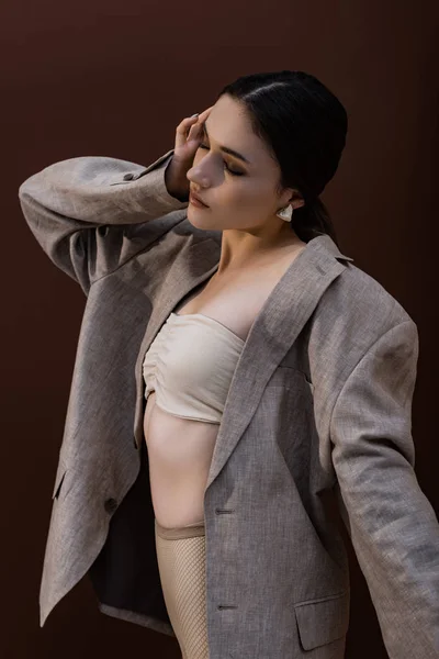 Молодая модель в нижнем белье и блейзере стоя на коричневом фоне — стоковое фото