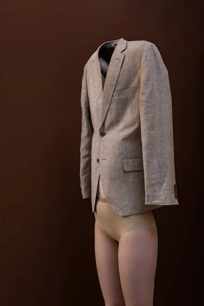 Donna adulta che tiene il blazer sopra la testa, in piedi su sfondo marrone — Foto stock
