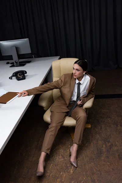 Vue grand angle de femme d'affaires en tenue formelle assis sur un fauteuil dans le bureau, regardant loin — Photo de stock
