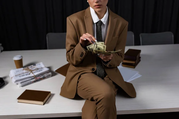 Vue recadrée d'une femme d'affaires prospère assise sur la table, croisant les jambes et comptant l'argent — Photo de stock