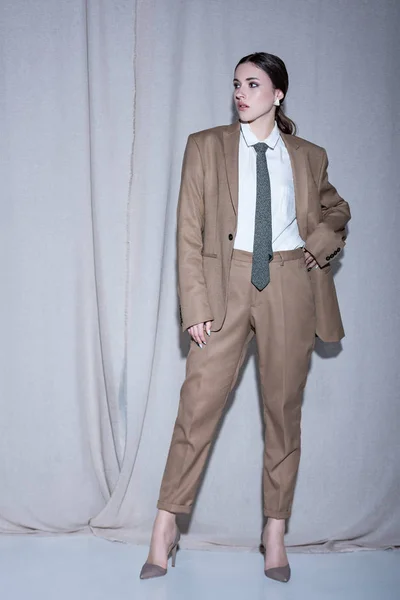 Erwachsenes Model im Anzug steht auf hellgrauem Vorhang-Hintergrund und schaut weg — Stockfoto