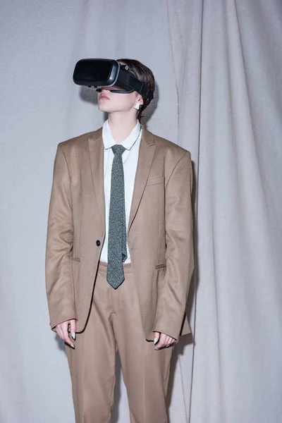 Успешная женщина в наушниках VR стоя на светло-сером фоне занавески — стоковое фото