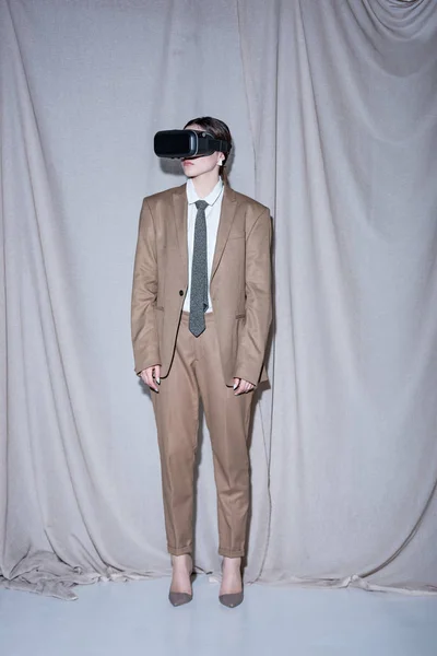 Woman in vr headset and suit standing on curtain background — Stock Photo