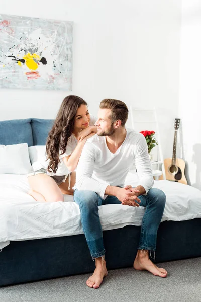 Petite amie souriante regardant petit ami au lit le matin — Photo de stock