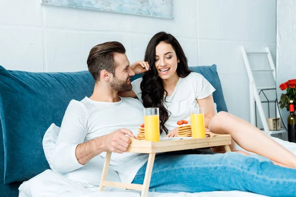 Smiling happy couple having breakfast in bed at morning — Stock Photo