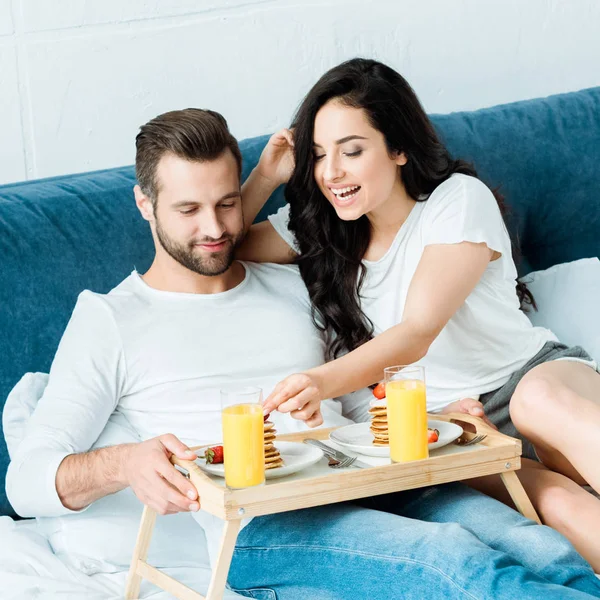 Glückliches Paar mit Orangensaft und Pfannkuchen zum Frühstück im Bett — Stockfoto