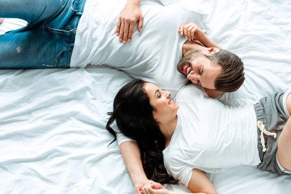 Top view of happy couple lying together in bed and looking at each other — Stock Photo