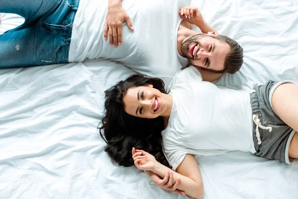 Vista superior de feliz sonriente pareja acostados juntos en la cama - foto de stock