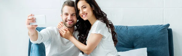 Feliz pareja tomando selfie en smartphone en la cama - foto de stock