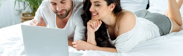 Casal feliz usando laptop juntos enquanto deitado na cama, editorial ilustrativo — Fotografia de Stock