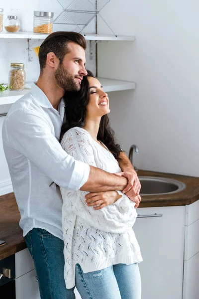 Homem sonhador gentilmente abraçando mulher feliz em casa — Fotografia de Stock