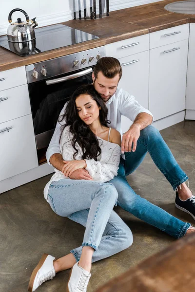 Vue aérienne du couple assis sur le sol et étreignant la cuisine — Photo de stock