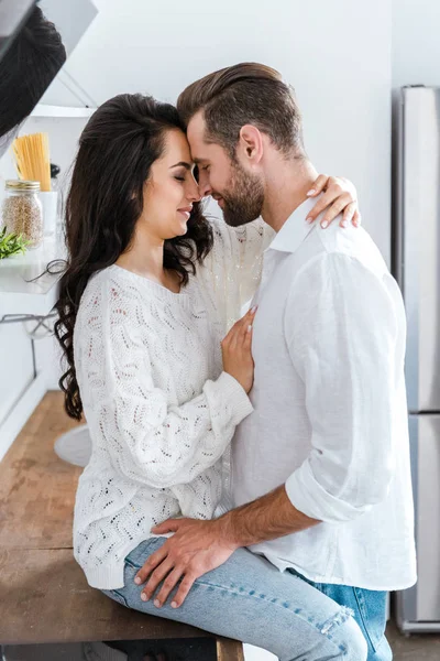 Homem e mulher gentilmente abraçando na cozinha — Fotografia de Stock