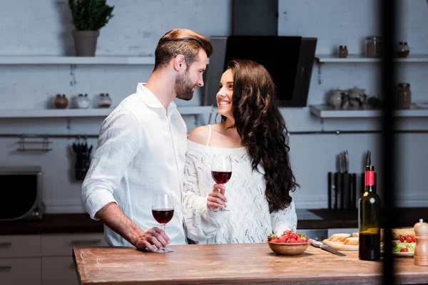 Glückliches Paar hält Gläser mit Rotwein in der Hand und schaut sich an — Stockfoto