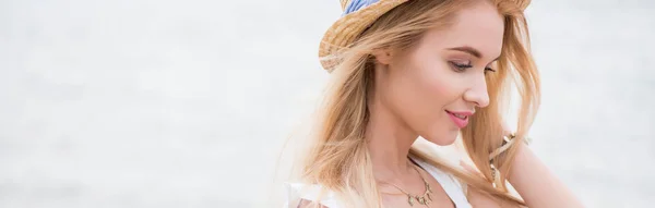 Панорамний знімок красивої і веселої блондинки в солом'яному капелюсі біля моря — стокове фото