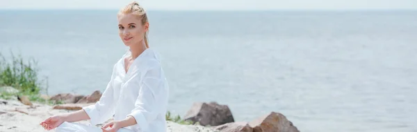 Plano panorámico de mujer rubia feliz practicando yoga - foto de stock