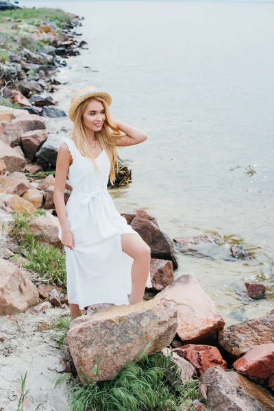 Heureuse et belle jeune femme souriante tout en se tenant près de la mer — Photo de stock