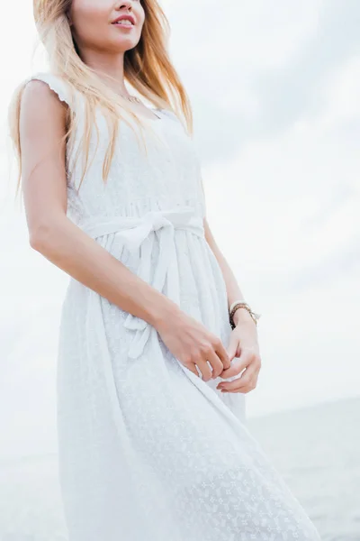 Baixo ângulo de visão da jovem mulher feliz de pé em vestido branco — Fotografia de Stock
