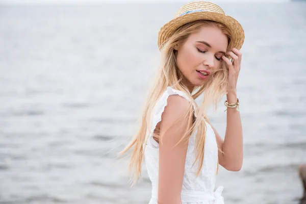 Красива блондинка з закритими очима торкається волосся біля моря — стокове фото