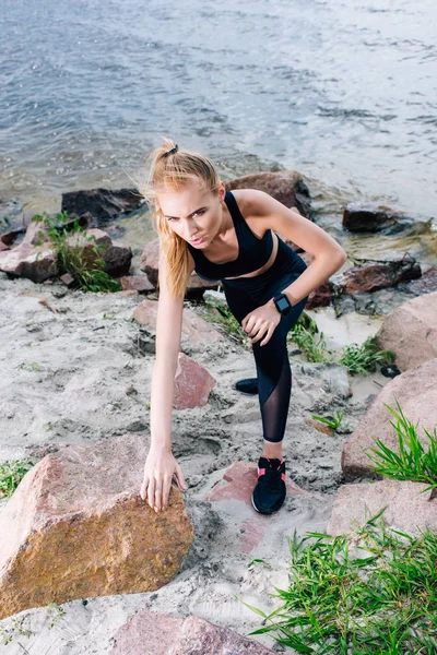 Vue aérienne d'une jolie sportive blonde en tenue de sport grimpant près de pierres — Photo de stock