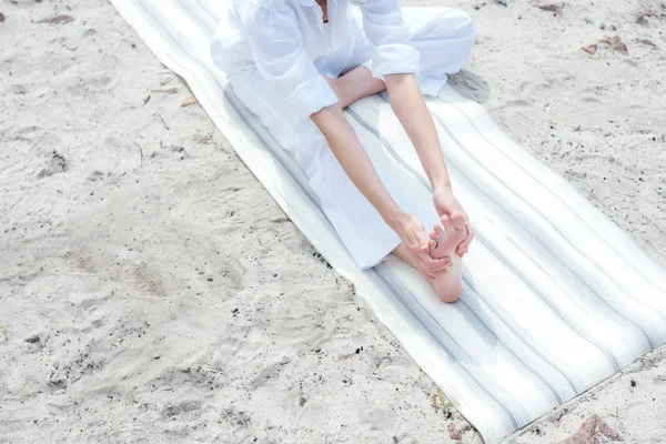 Vue recadrée de la jeune femme étirant sur tapis de yoga sur la plage — Photo de stock