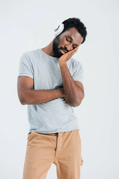 Втомлений афроамериканський чоловік слухає музику з навушниками, ізольований на сірому — стокове фото