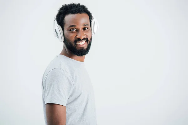 Lächelnder afrikanisch-amerikanischer Mann, der Musik mit Kopfhörern hört, isoliert auf grau — Stockfoto