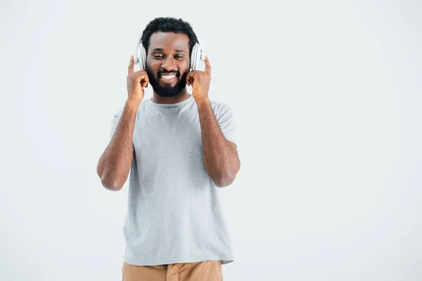 Happy african american man listening music with headphones, isolated on grey — Stock Photo