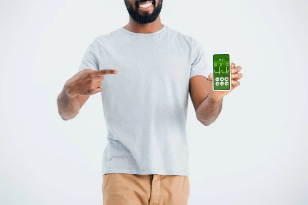 Vista recortada del hombre afroamericano apuntando al teléfono inteligente con aplicación de salud, aislado en gris - foto de stock