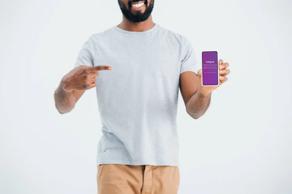 KYIV, UKRAINE - MAY 17, 2019: cropped view of african american man pointing at smartphone with instagram app, isolated on grey — Stock Photo